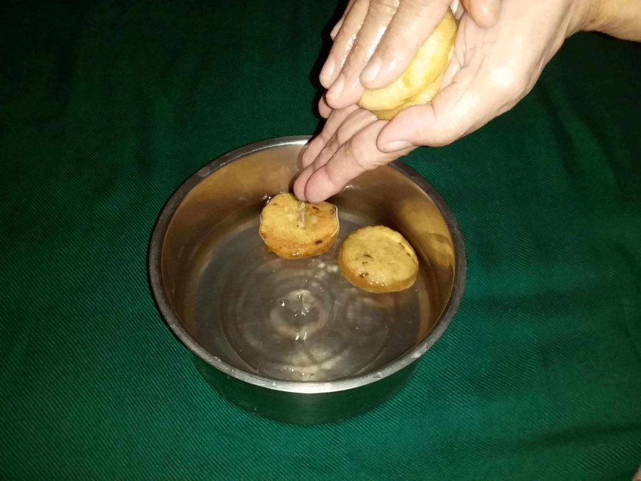 Pressing out the extra water from Vada, as described in Recipe of Dahi Vada.
