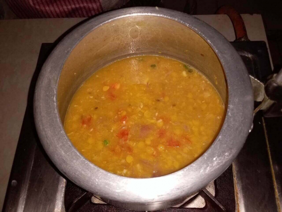Dal mixture being cooked in cooker after addition of Tadka in Recipe of Chana Dal.