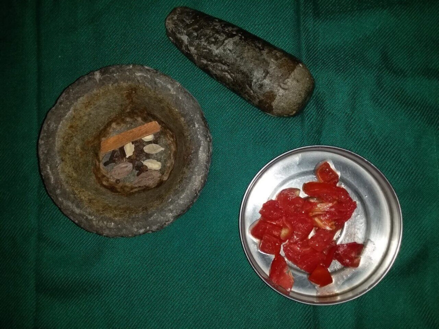 Whole Garam masala in pestle for crushing & cut Tomato pieces as described in Fish Kalia Recipe.