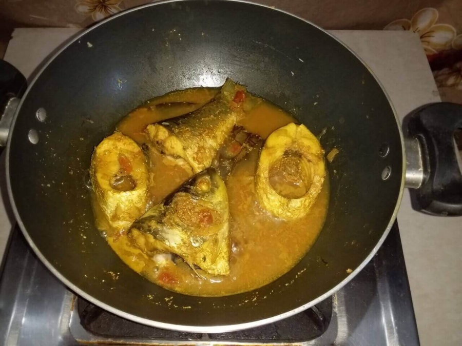 Fish pieces being cooked in gravy mixture as described in Fish Kalia Recipe.