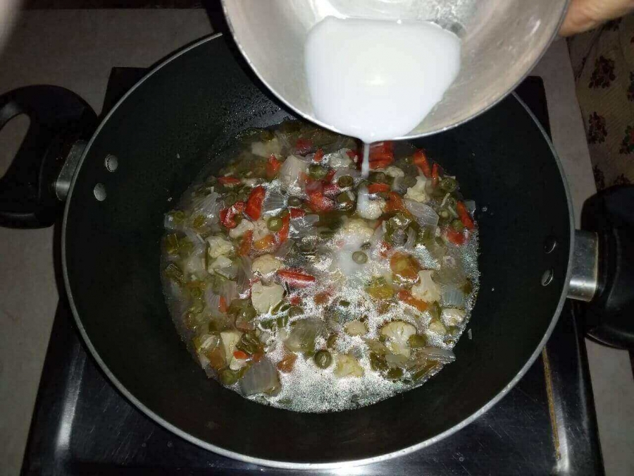 Corn starch being added to the preparation in Recipe for vegetable clear soup.