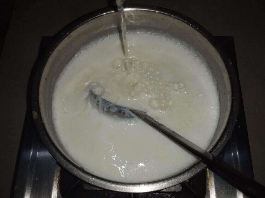 Lime water being added to the milk, as described in Recipe of Chenna Poda.