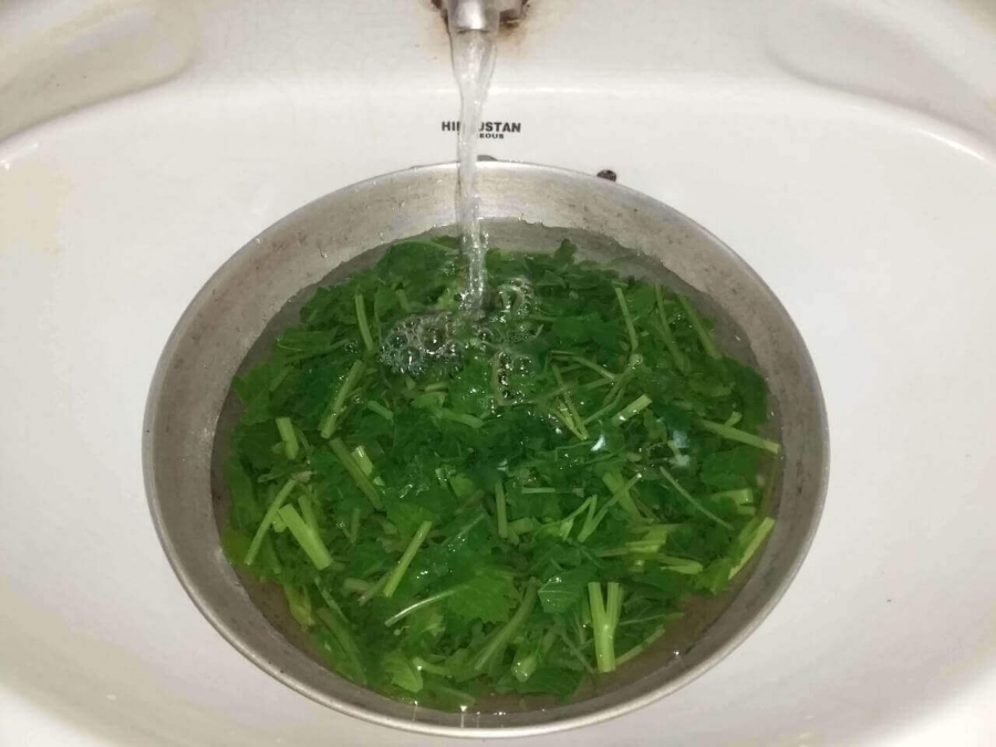 Sag mixture being washed in cold water for Blanching process  in Recipe of Sarson Ka Saag.