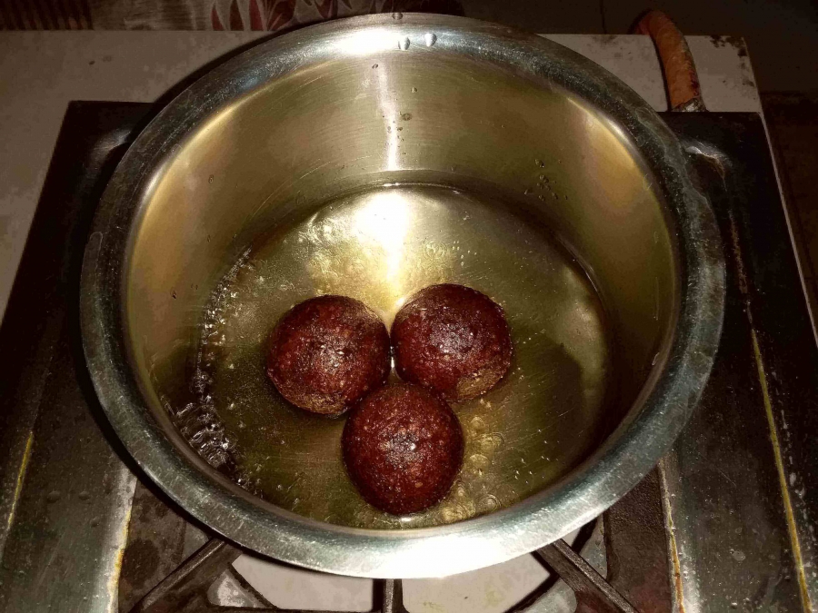 Soaking Gulab Jamuns in Sugar Syrup in Recipe of Gulab Jamun with Milk Powder.