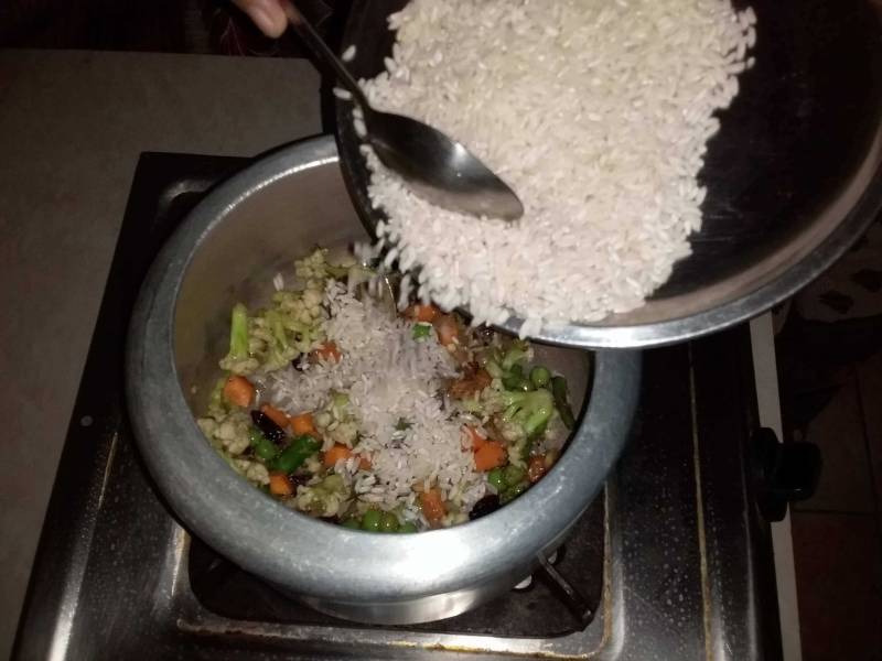 Rice being mixed with the vegetables as described in Recipe for Veg Pulao.