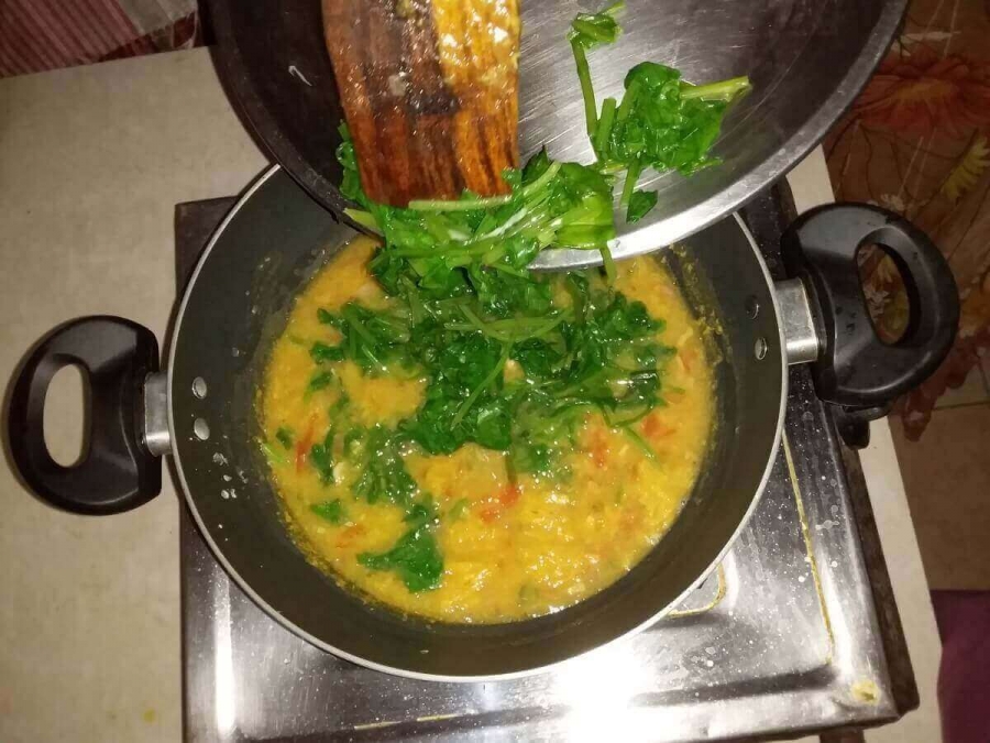 Blanched Spinach being added to the Dal mixture in Dal Palak Recipe.